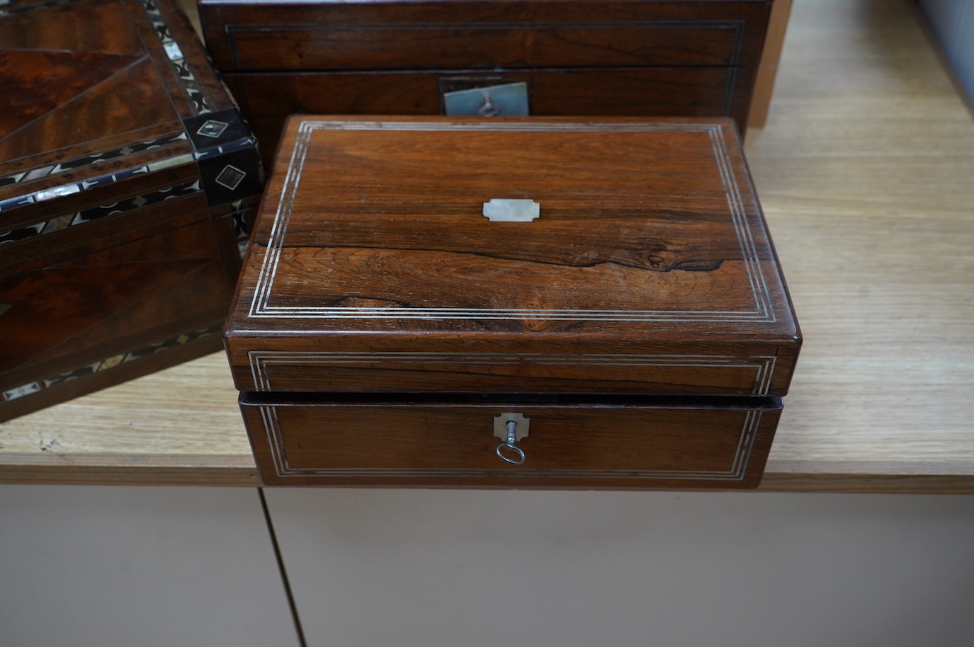 Three 19th century vanity and sewing boxes with fitted interiors to include a mother of pearl inlaid example with glass bottles, jars and mirror, largest 35cm wide. Condition - fair, some losses